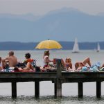 Zahlreiche Badegäste liegen auf einem Steg am Starnberger See. Sonne und Temperaturen von knapp 30 Grad Celsius locken die Menschen an. Foto: dpa