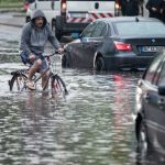 In Duisburg kämpft sich ein Radfahrer durch die meterhohe Flut. Foto: dpa